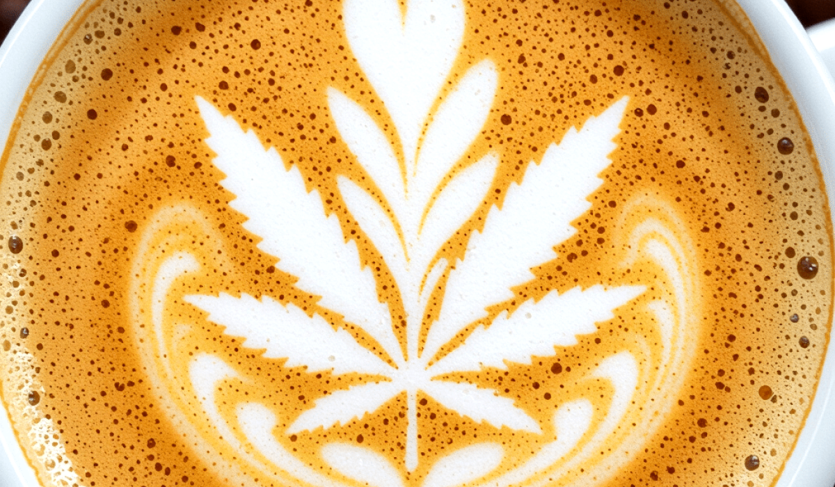 A cup of cannabis coffee with latte art resembling a cannabis leaf design on the foam.